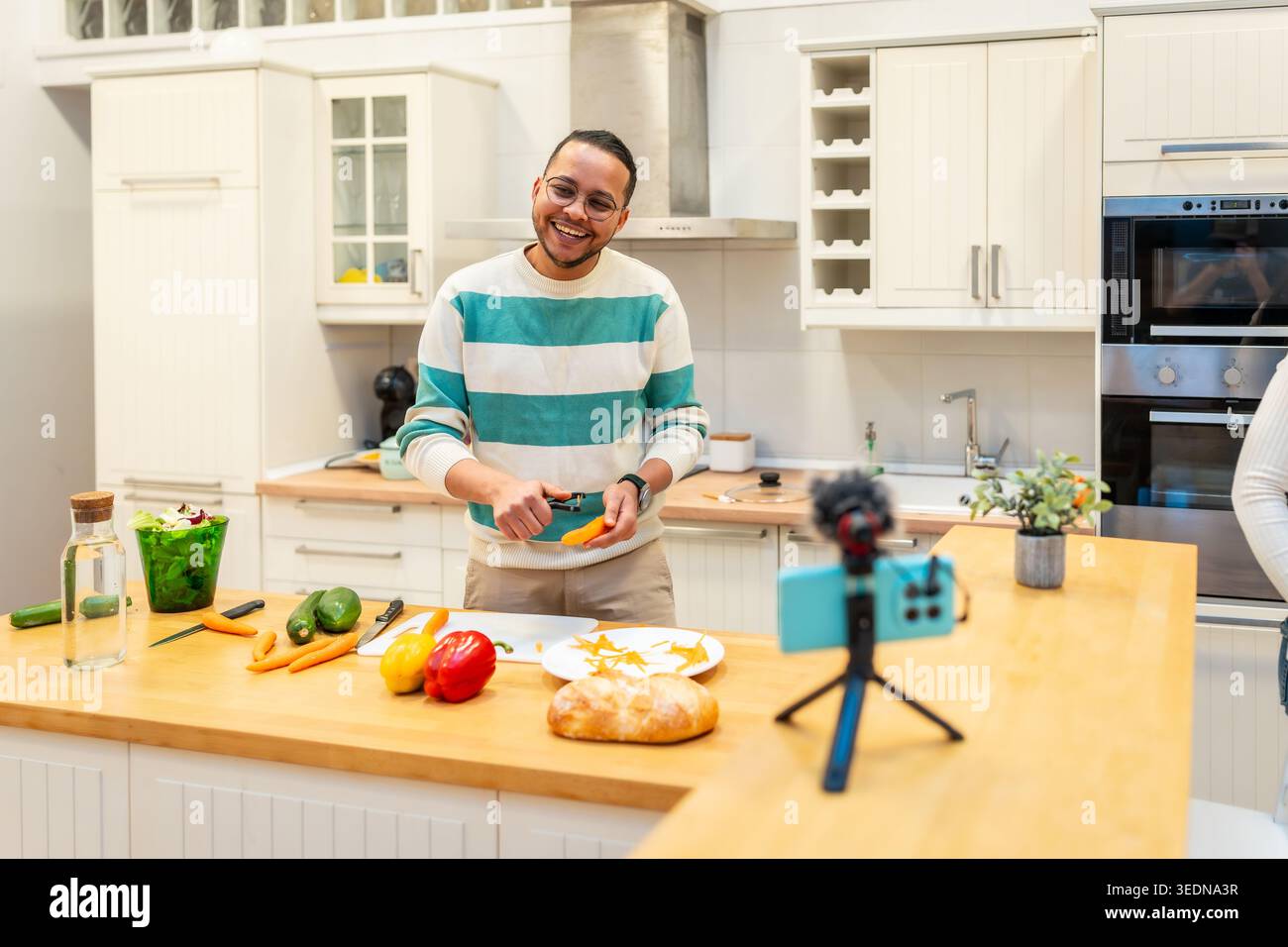 Influencer peeling vegetables for cooking video content Stock Photo