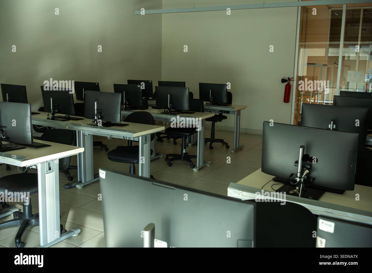 Dark Empty Computer Lab with Rows of Monitors in Dim Light Stock Photo