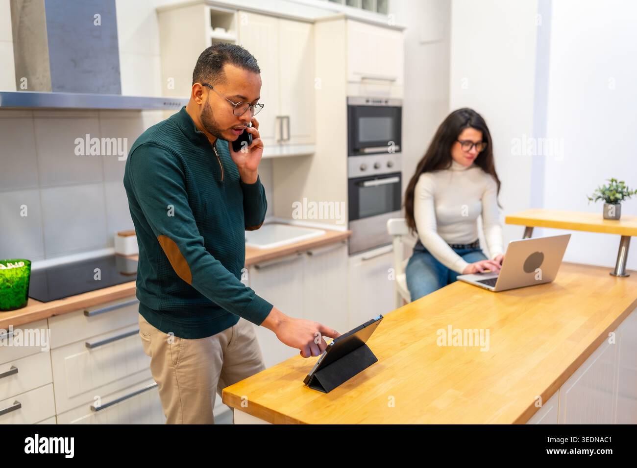 Young couple engaged in remote work in modern kitchen Stock Photo