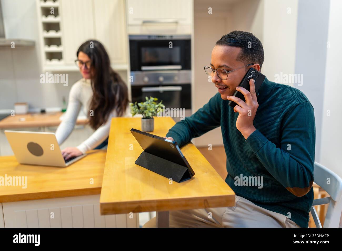 Couple working remotely in kitchen communicating and collaborating from home Stock Photo
