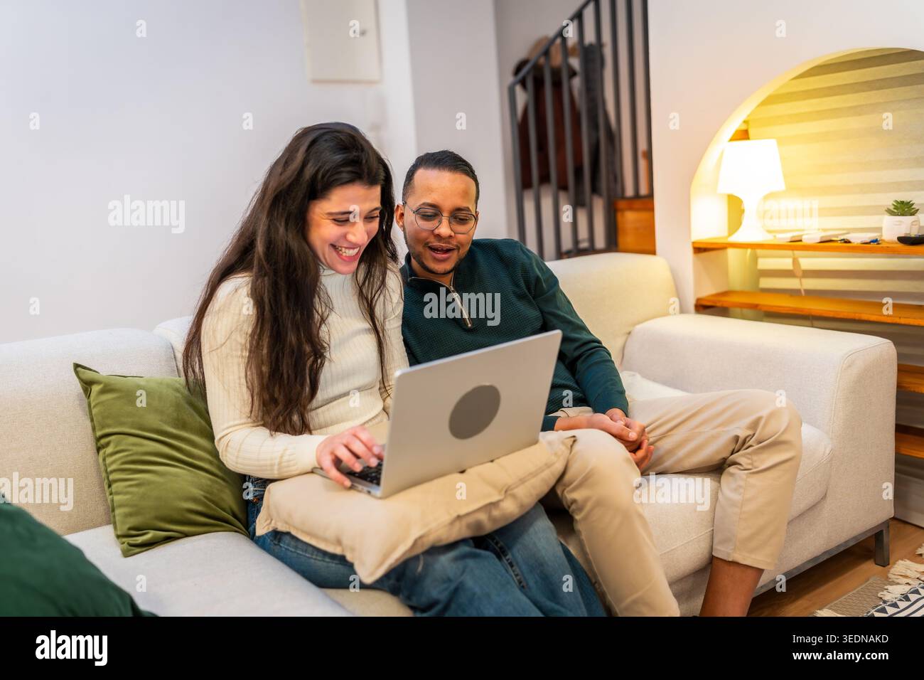 Happy couple relaxing on sofa using laptop together Stock Photo