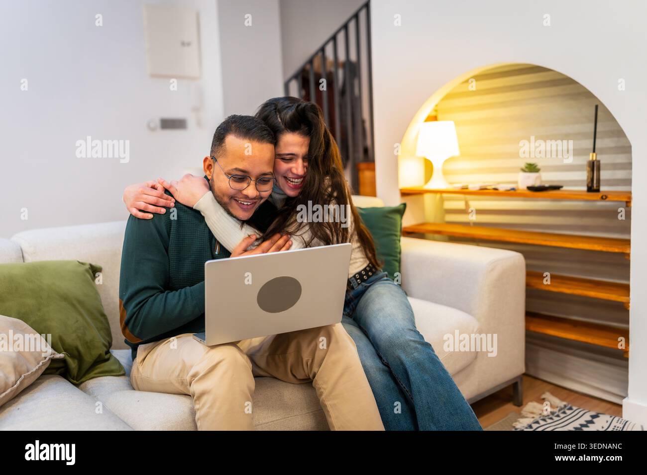 Happy couple laughing watching content on laptop Stock Photo