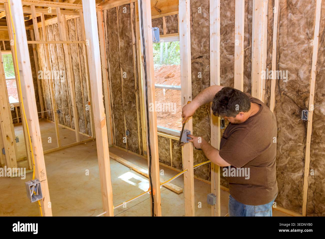Worker uses measuring tool to mark wooden studs inside house progress in construction site. Stock Photo