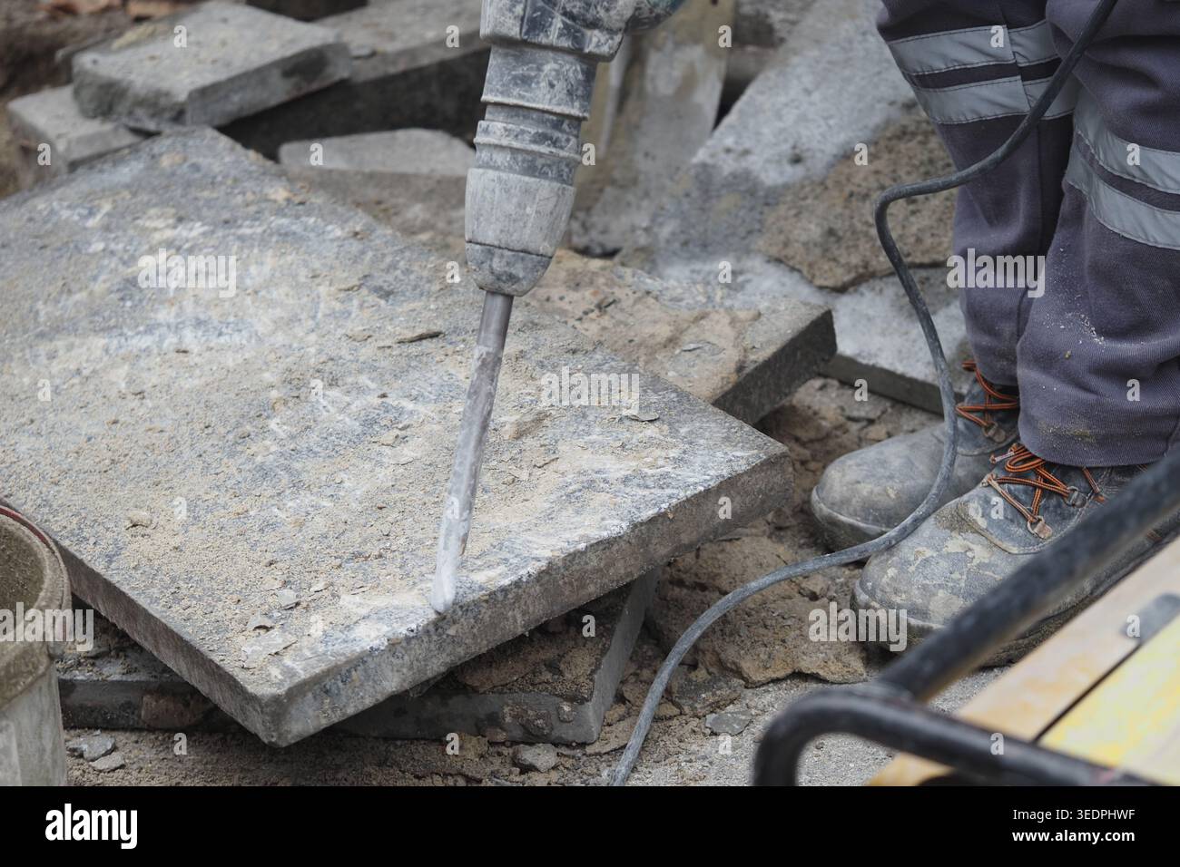 Construction worker uses jackhammer on pavement in a city Stock Photo