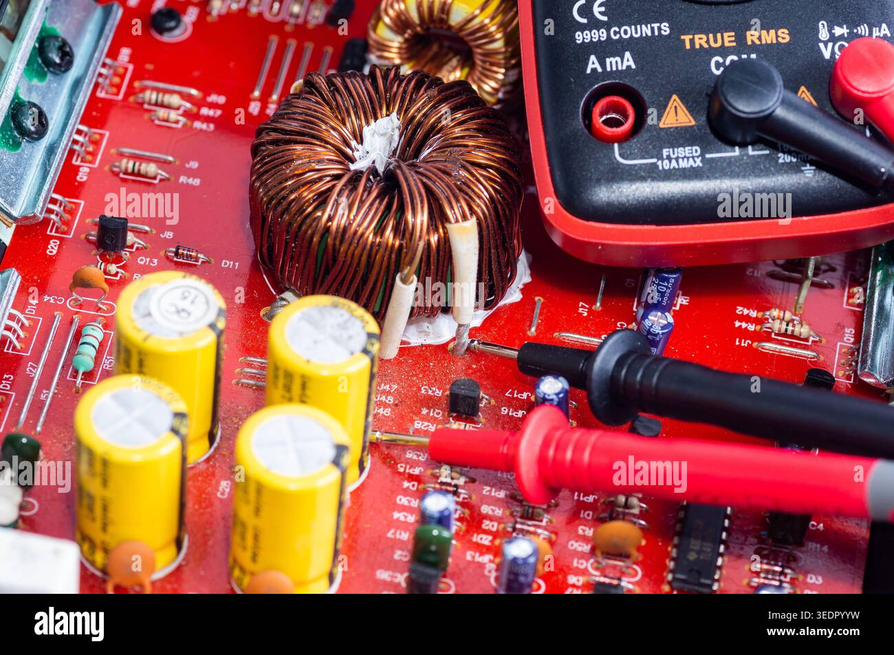 Multimeter with test probes and a circuit board Stock Photo