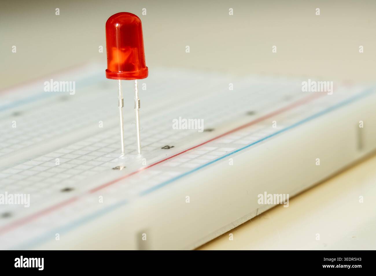 Red LED on breadboard close up, electronic component concept Stock Photo
