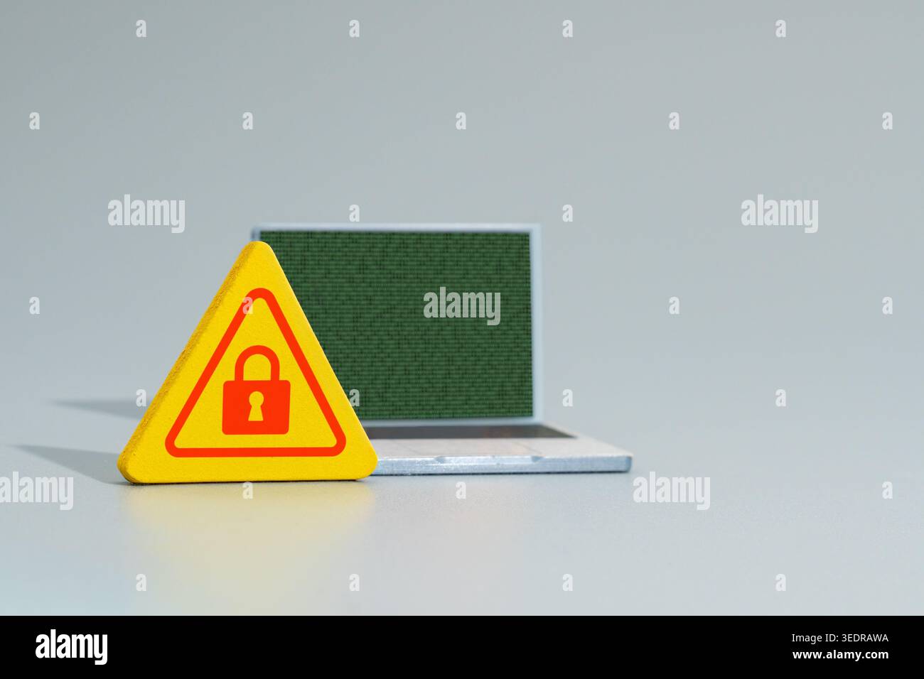 A warning sign with a red padlock icon and a laptop displaying green binary code. Cyber security, data encryption, ransomware concept. Stock Photo