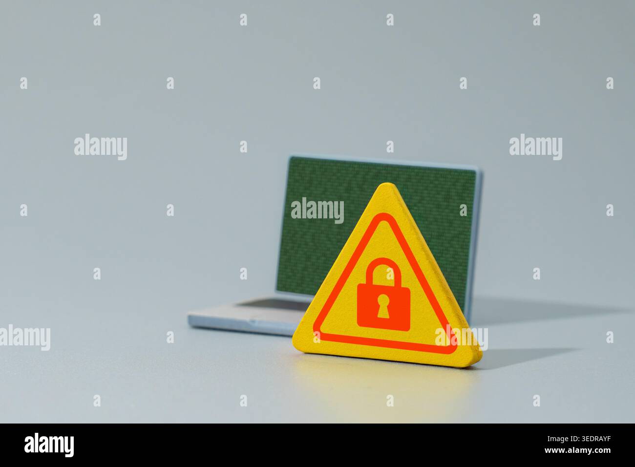 A warning sign with a red padlock icon and a laptop displaying green binary code. Cyber security, data encryption, ransomware concept. Stock Photo