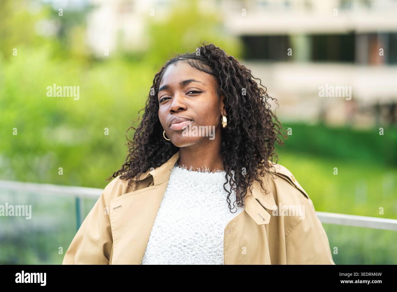 Confident fashionable african american young woman in fancy clothing posing at camera outdoors. Stock Photo