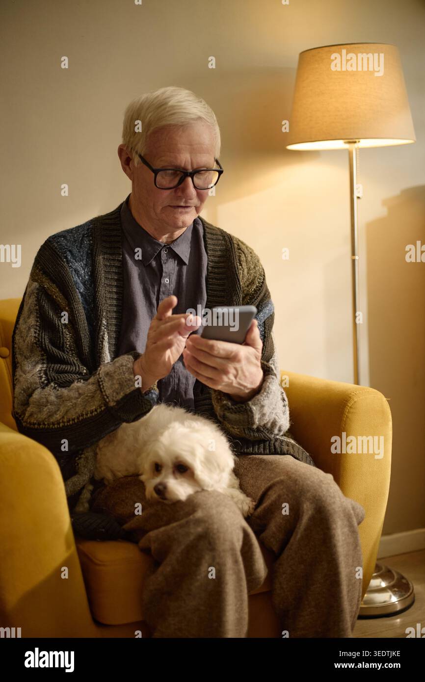 Senior Man Using Smartphone for Remote Communication at Home Stock Photo