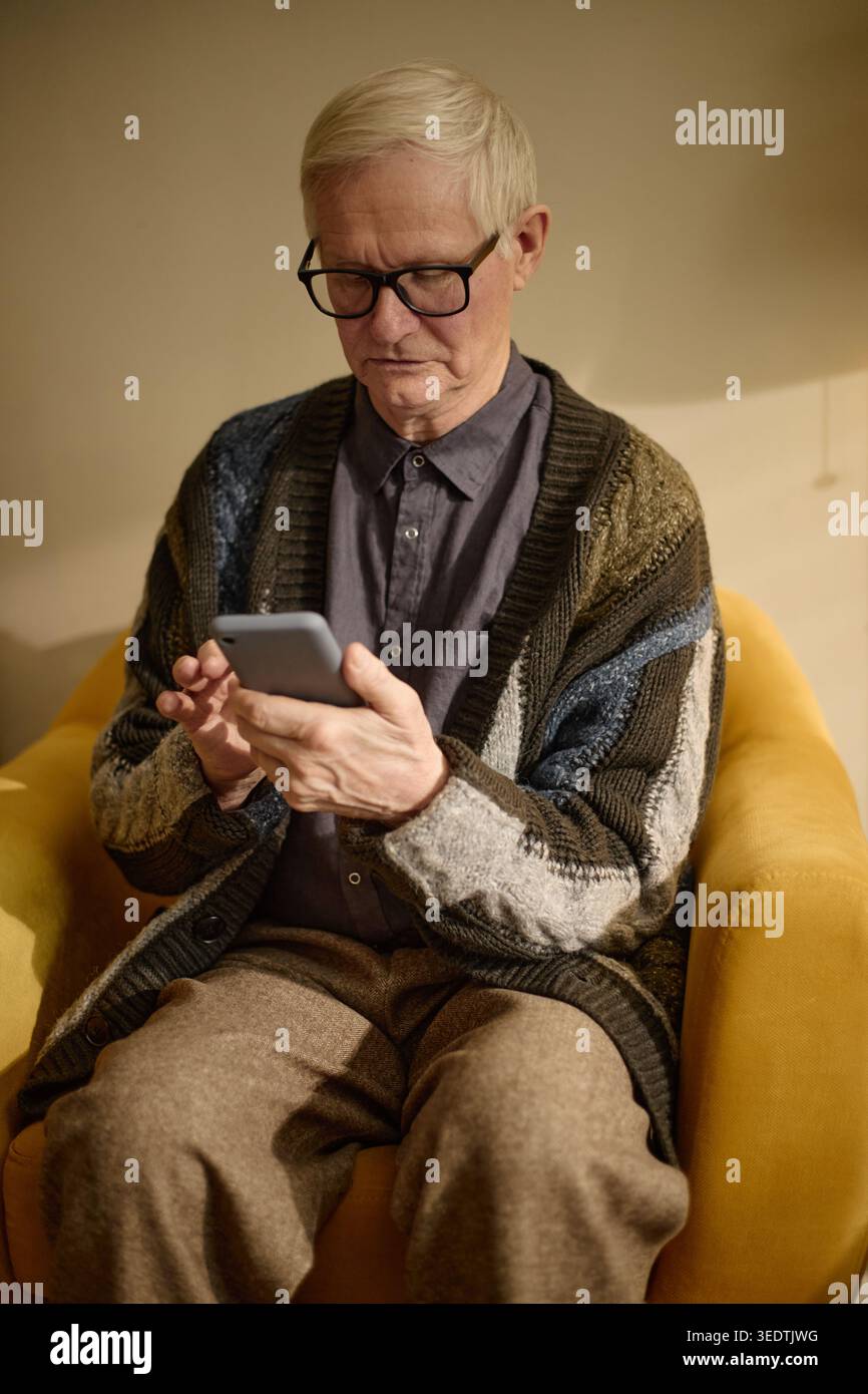 Senior Man Using Smartphone for Online Communication at Home Stock Photo