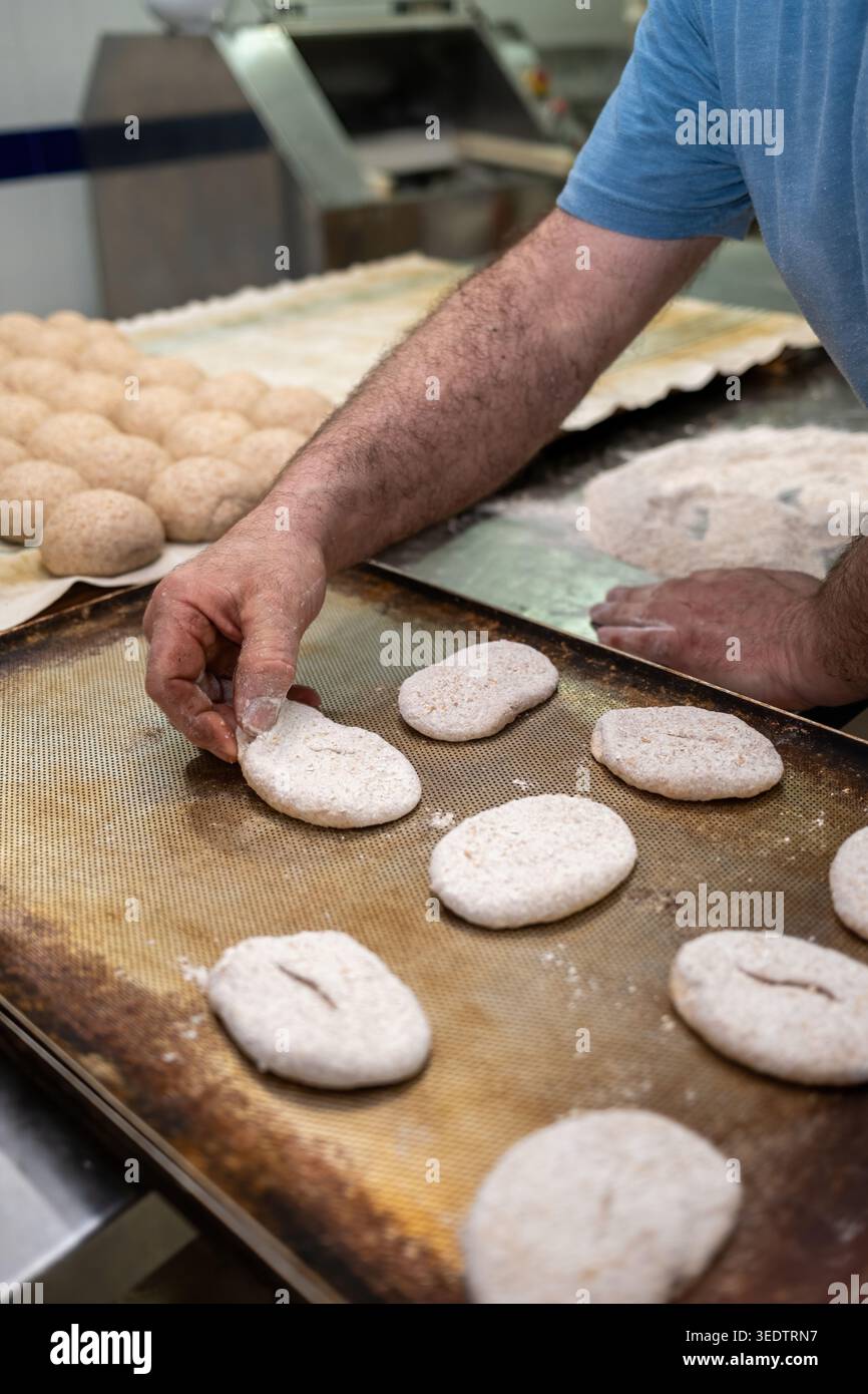 Baker preparing raw bread dough for baking Stock Photo