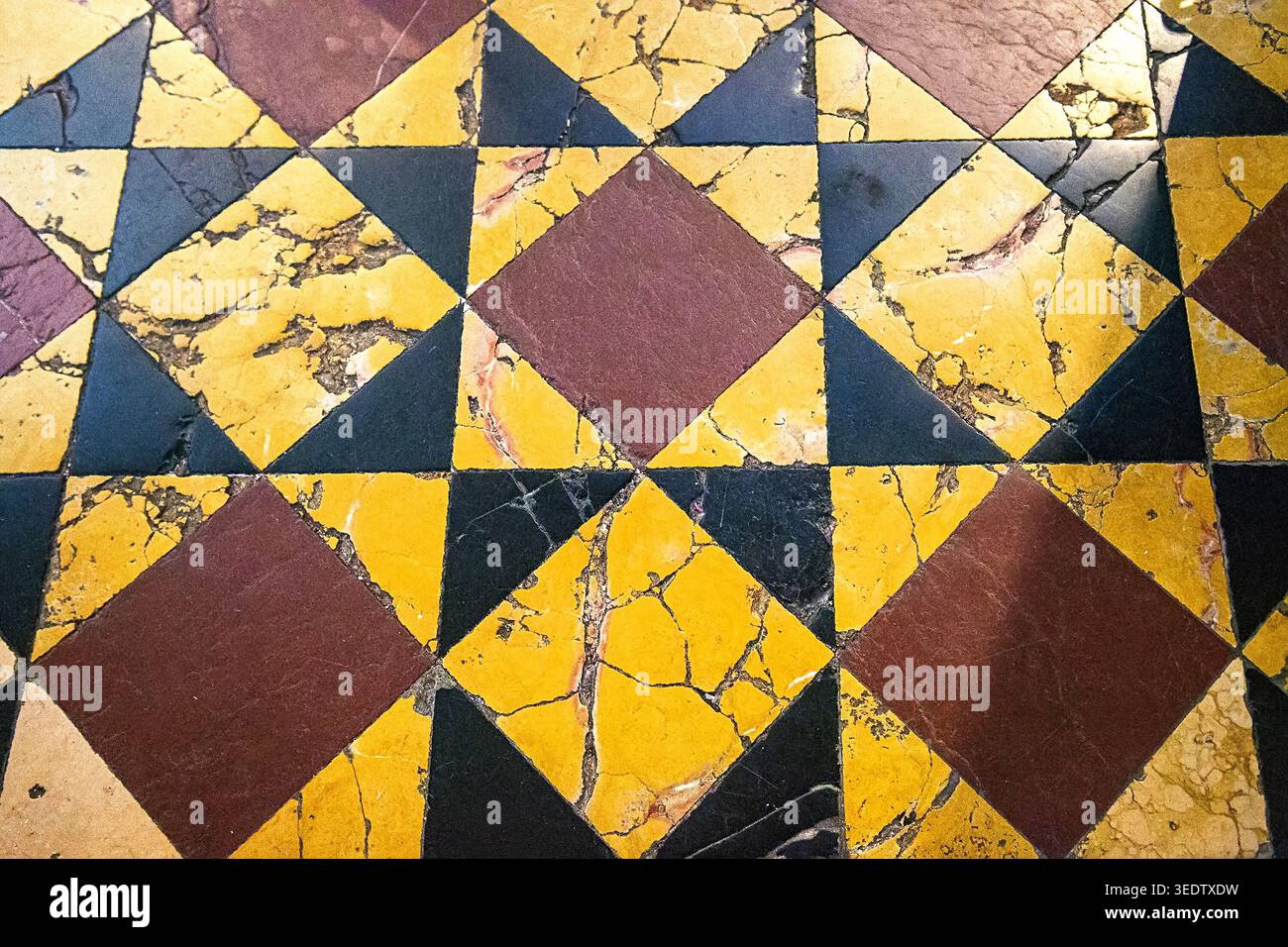 High angle view of an antique marble floor with a geometric star and diamond pattern using selective focus. The shallow depth highlights the authentic Stock Photo