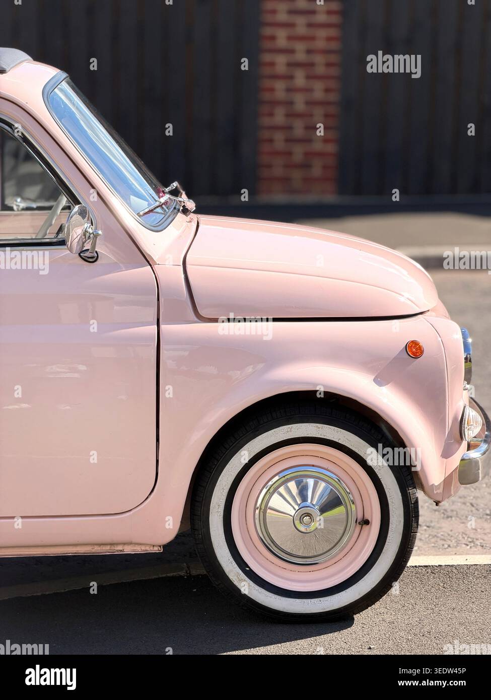Profile of a vintage pink classic 1960s Fiat 500 classic car with whitewall tires parked on a street - Smartphone Captured Stock Image