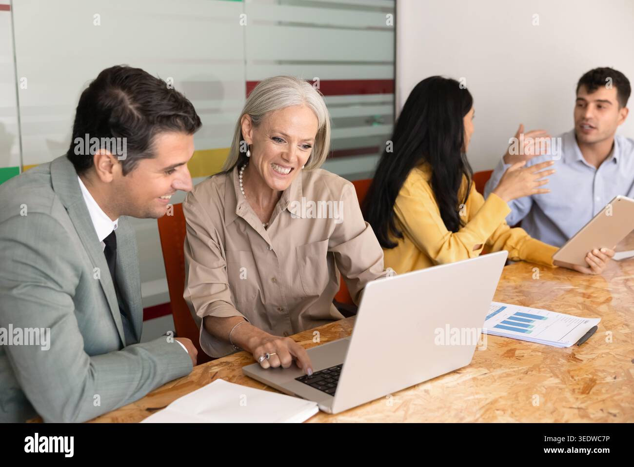 Corporate team members working together on project using laptop Stock Photo