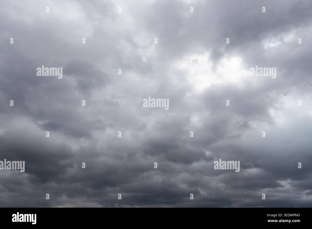 Dark storm clouds gathering across dramatic overcast sky before rain, moody weather background landscape Stock Photo