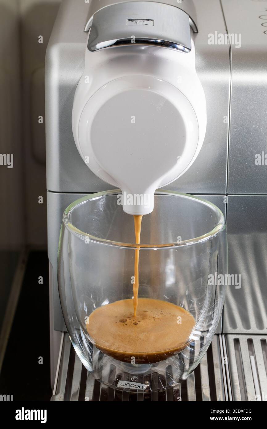 A Nespresso machine is pouring coffee from a placed cup. Stock Photo