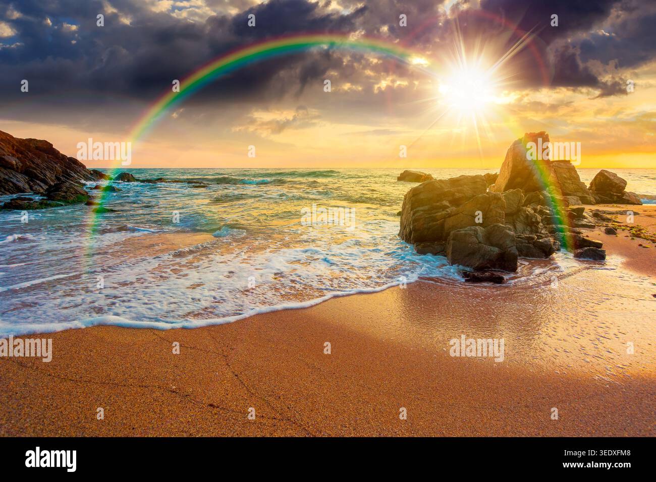 sunset over huge stones on the sandy beach. wonderful holiday season background at the sea. clouds on the blue sky above horizon. view of waves washin Stock Photo