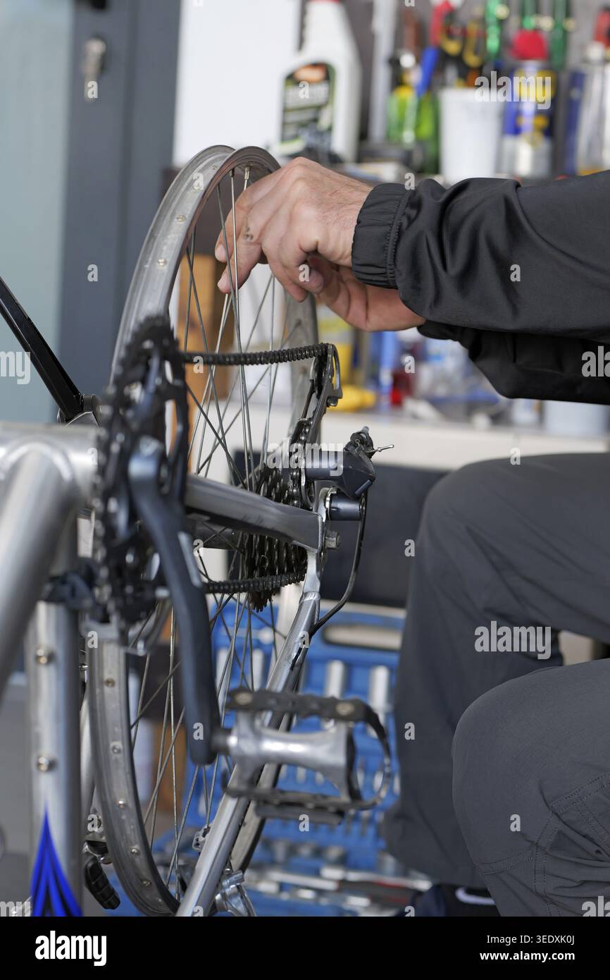 Bike mechanic checks rear wheel alignment and rim stability on upside ...