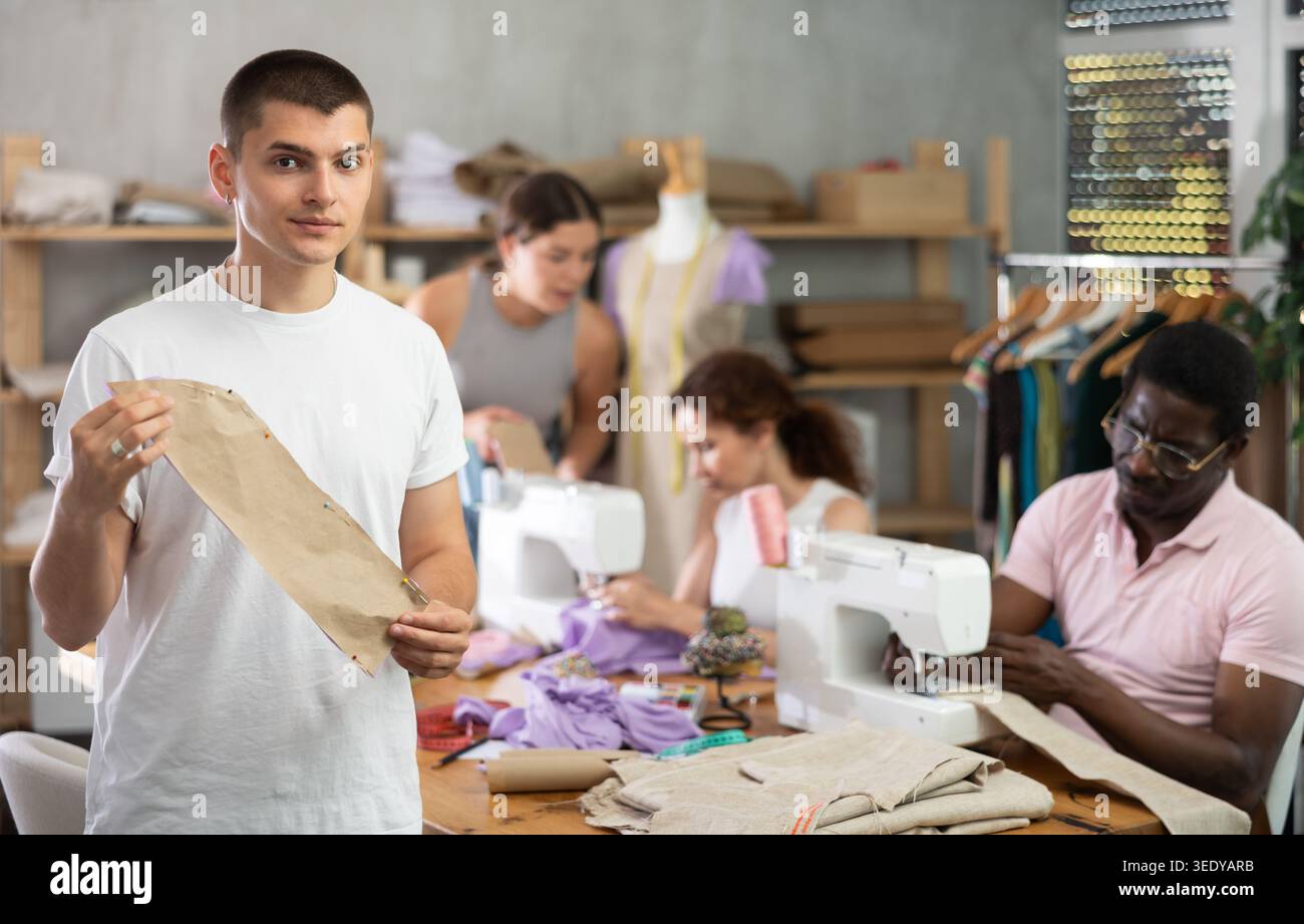 Young guy showing paper pattern in training sewing workshop Stock Photo
