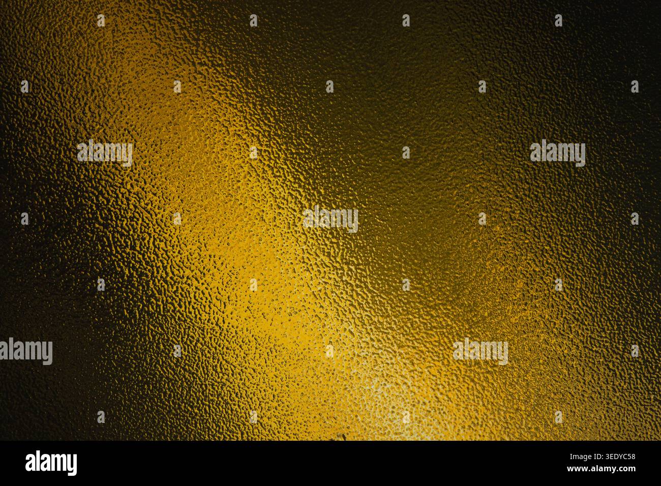 Dark gold and black frosted glass texture with diagonal light beam Stock Photo