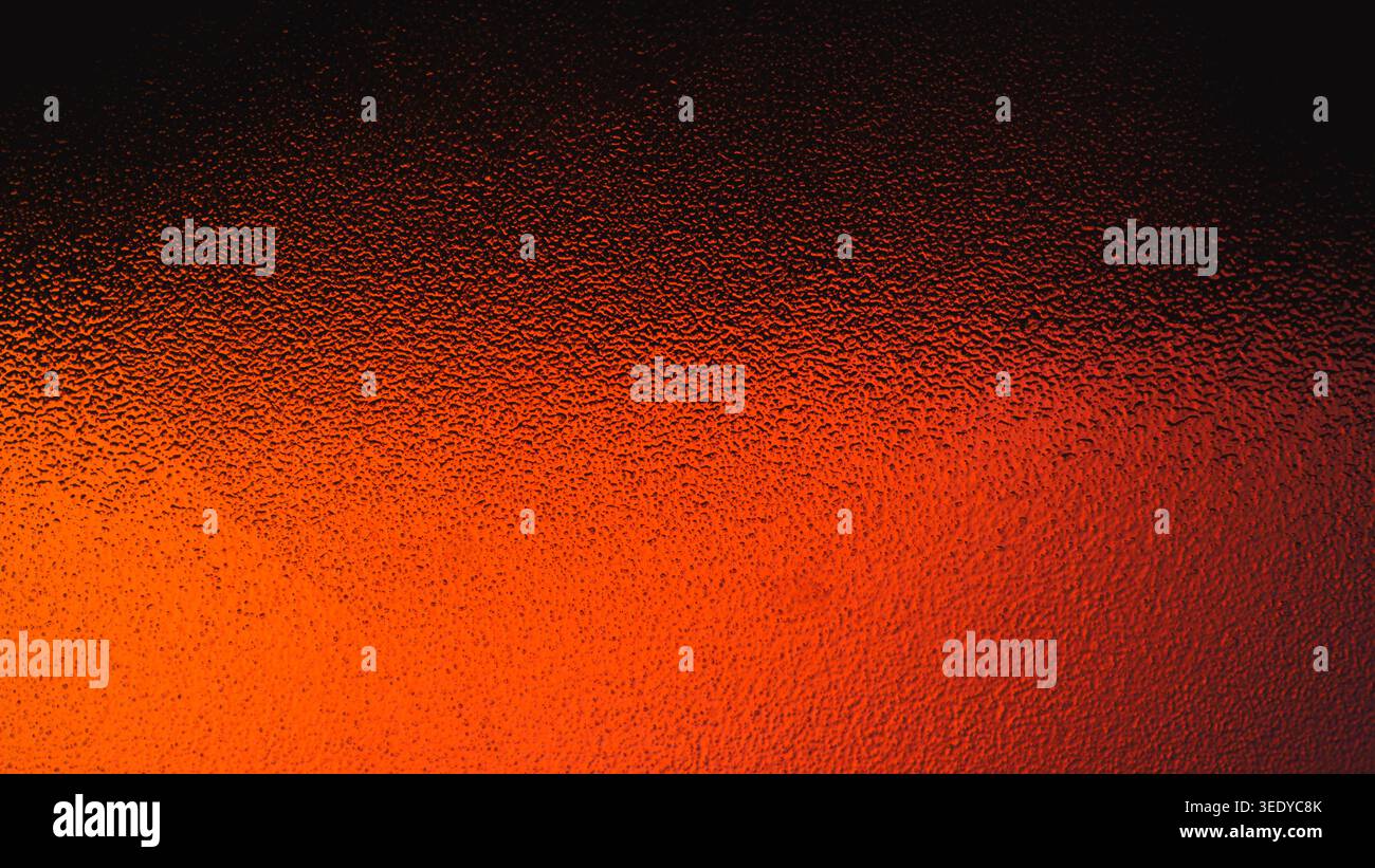 Intense fiery red and orange gradient showing through a bumpy glass texture Stock Photo