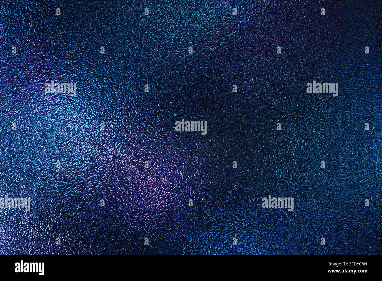 Iridescent blue and purple light reflecting on a bumpy glass texture Stock Photo