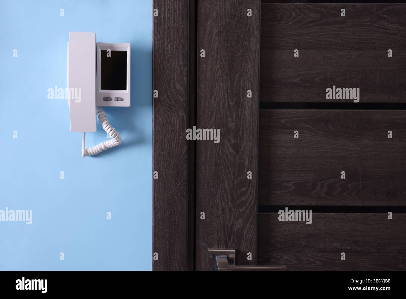 Modern intercom system with handset on light blue wall indoors Stock Photo