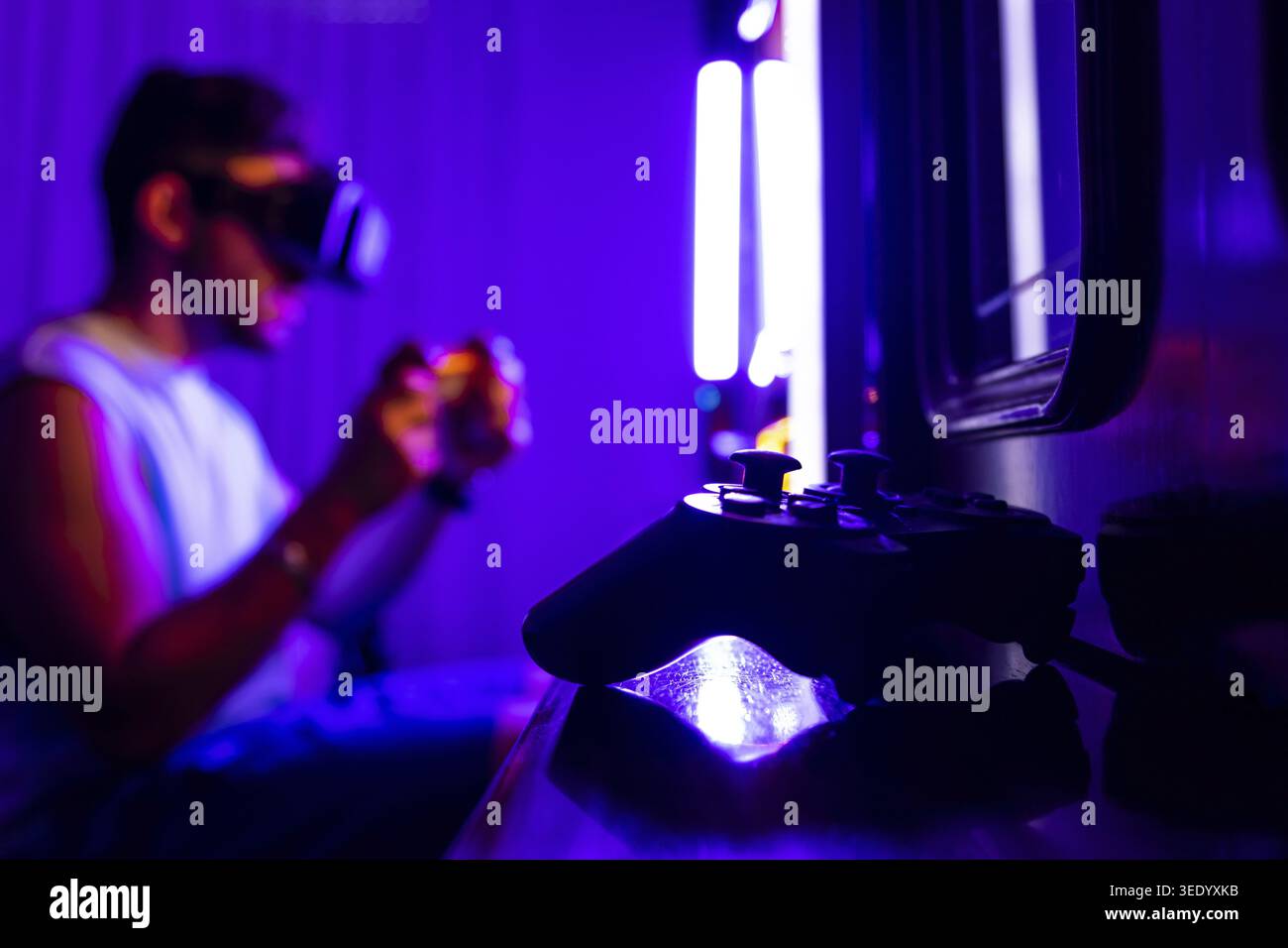 Close-up of a video game controller. In the background a man plays console with virtual reality goggles Stock Photo