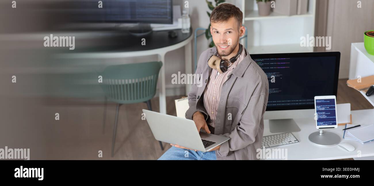 Young programmer working with laptop in office. Banner for design Stock Photo