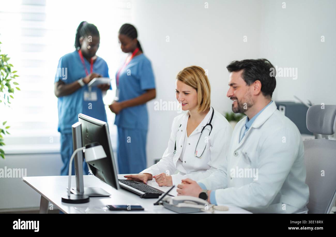Doctors and nurses collaborating in medical office using a computer Stock Photo