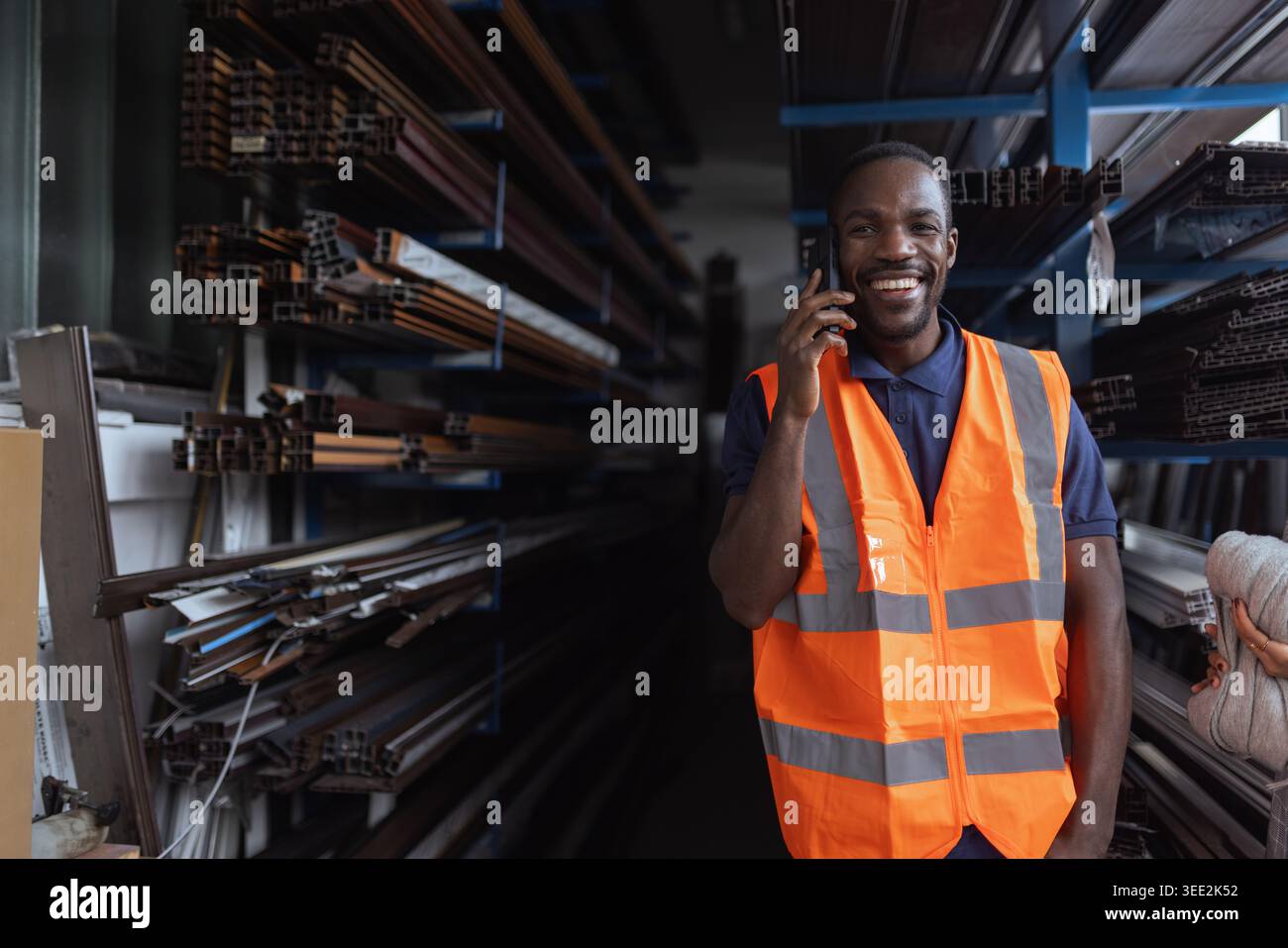 African American factory worker checks equipment and talking on phone in industrial setting. Stock Photo