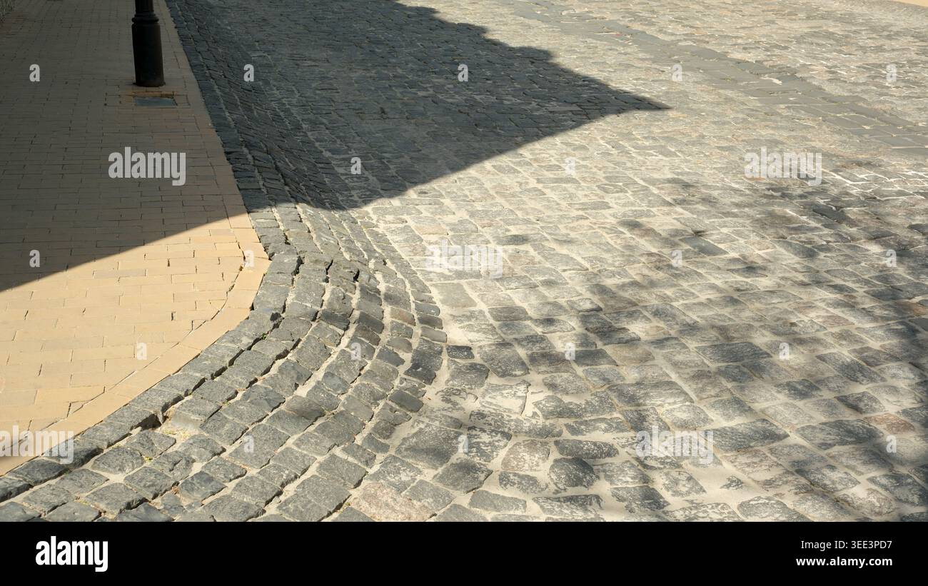 A winding cobblestone path meanders under the warm afternoon light creating shadows. Stock Photo