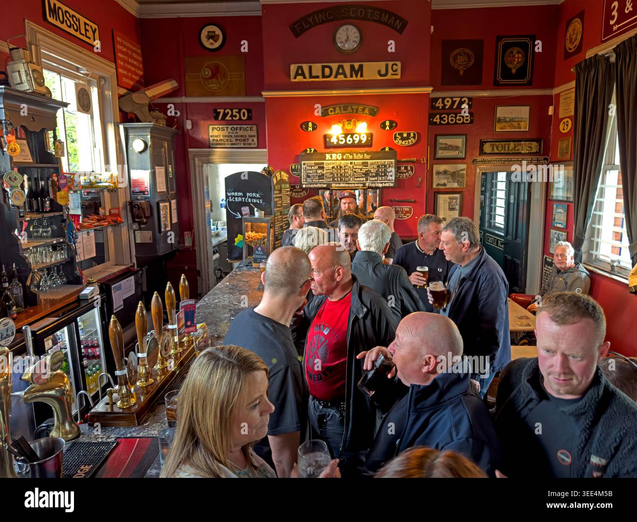Busy CAMRA-listed Stalybridge Victorian Buffet Bar with cask ale handpumps, railway memorabilia and drinkers inside the 1885 station pub. Stock Photo