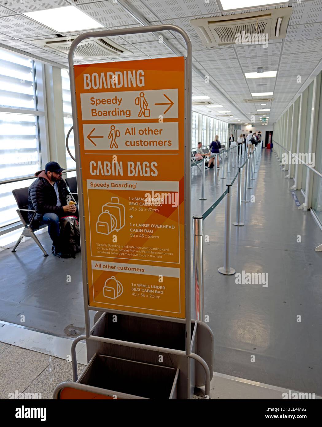 EasyJet cabin bag sizer at a Catania Airport departure gate, with Speedy Boarding and standard passenger directions. Stock Photo