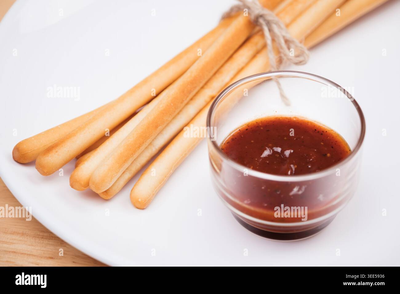 pack of breadsticks with ketchup dipping sauce in white dish on wood table Stock Photo