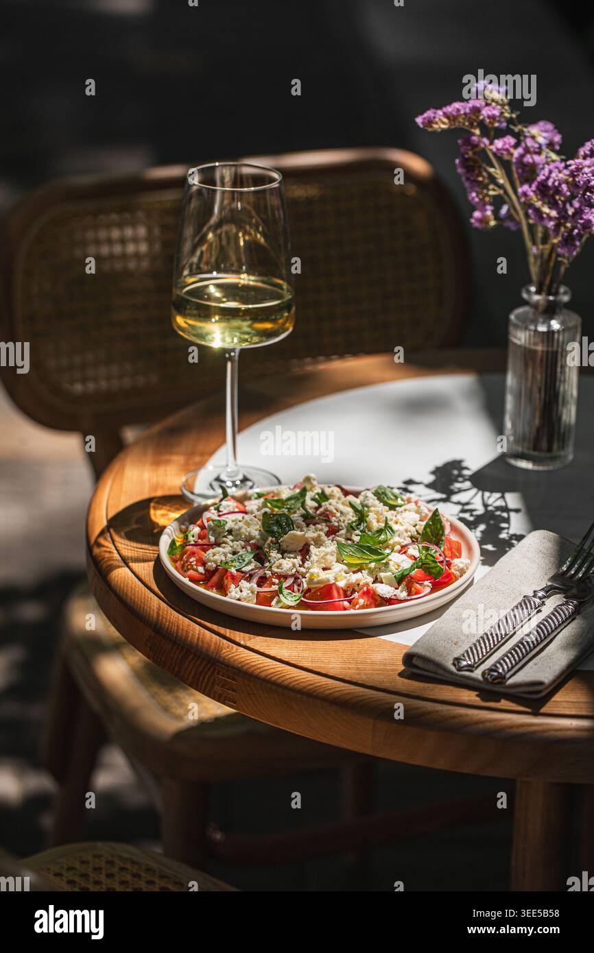 Mediterranean salad with wine on sunny table Stock Photo