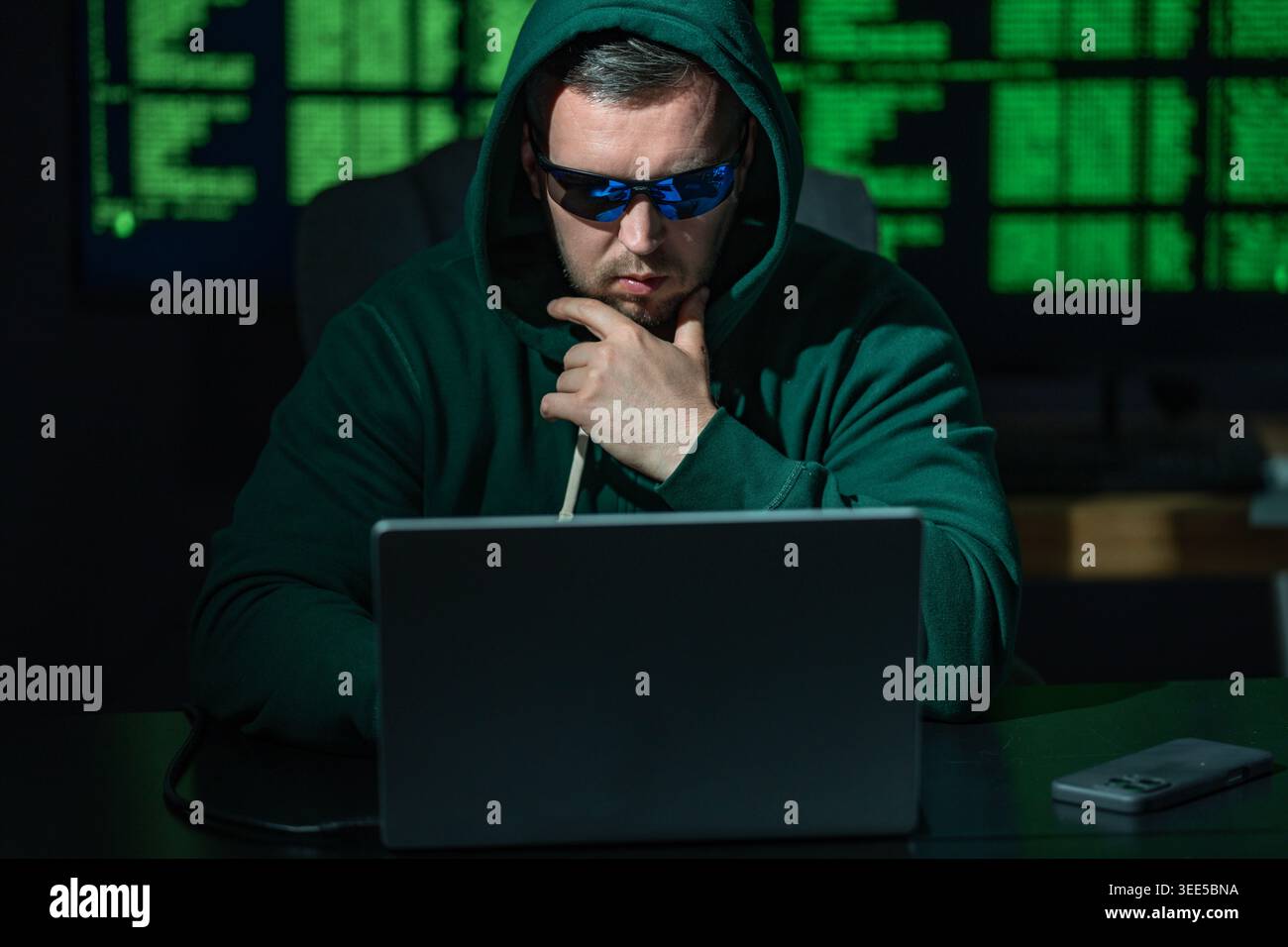 Hacker types code with concentration. Hacker analyzes network security system. Hacker monitors online data transmission. Hacker executes phishing Stock Photo