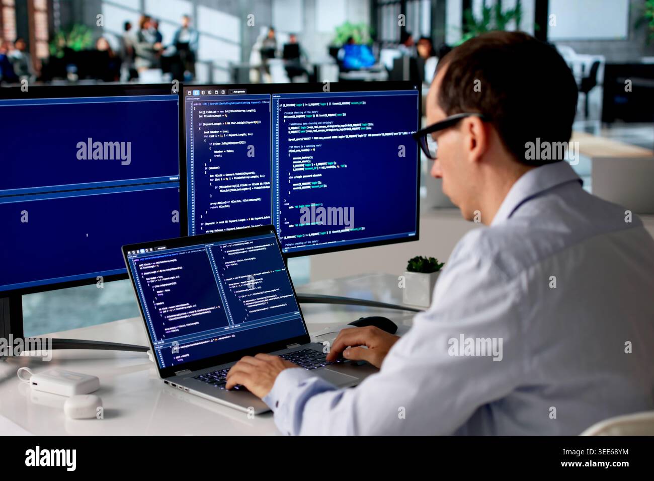 Man In Office Focused On Coding New Web Project Using Laptop Computer. Stock Photo