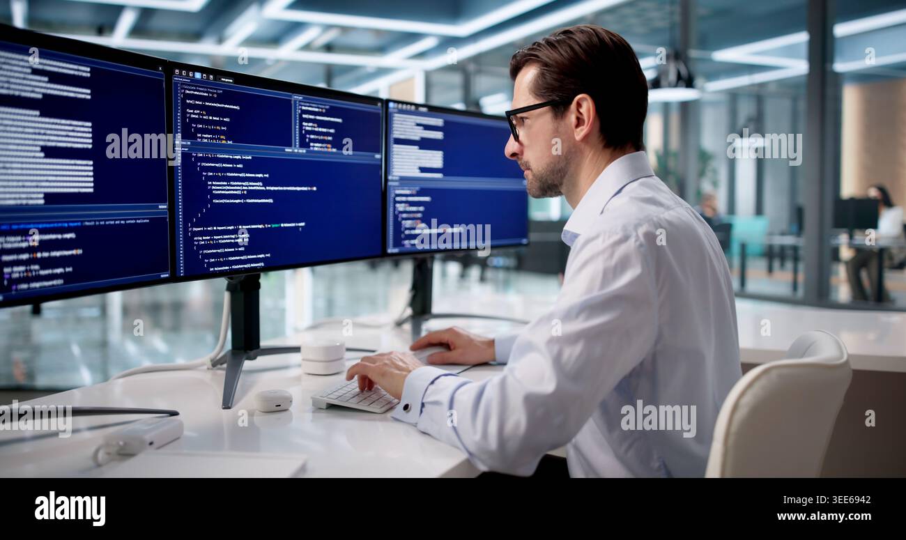 Man Focused On Coding Software At Desk In Quiet Office Space. Stock Photo