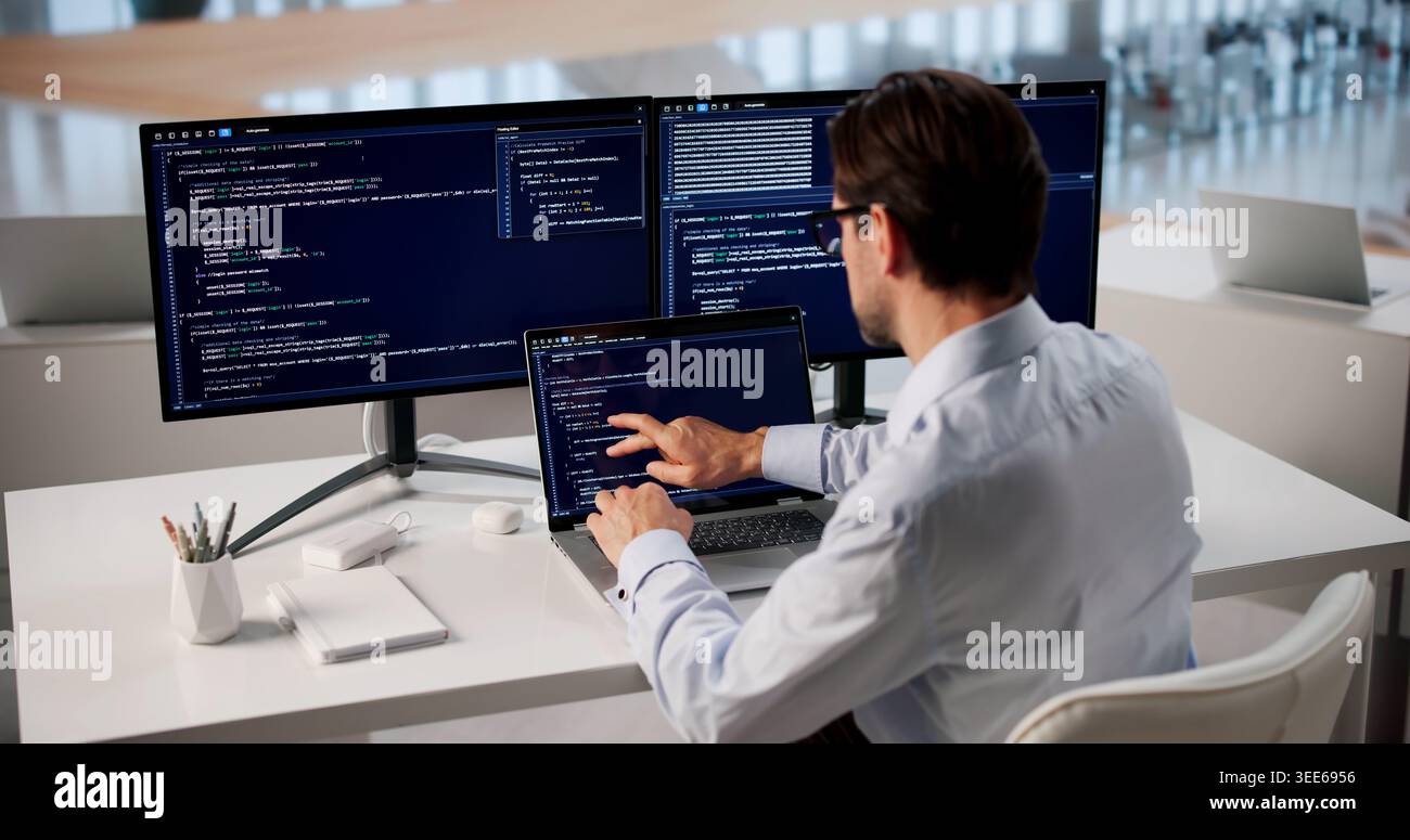 Focused Man Typing Code On Laptop At Modern Office Workspace. Stock Photo
