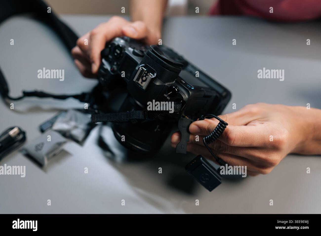Close-up view of content creator hands setting up and synchronizing wireless lapel microphone system, connecting receiver to digital camera for profes Stock Photo