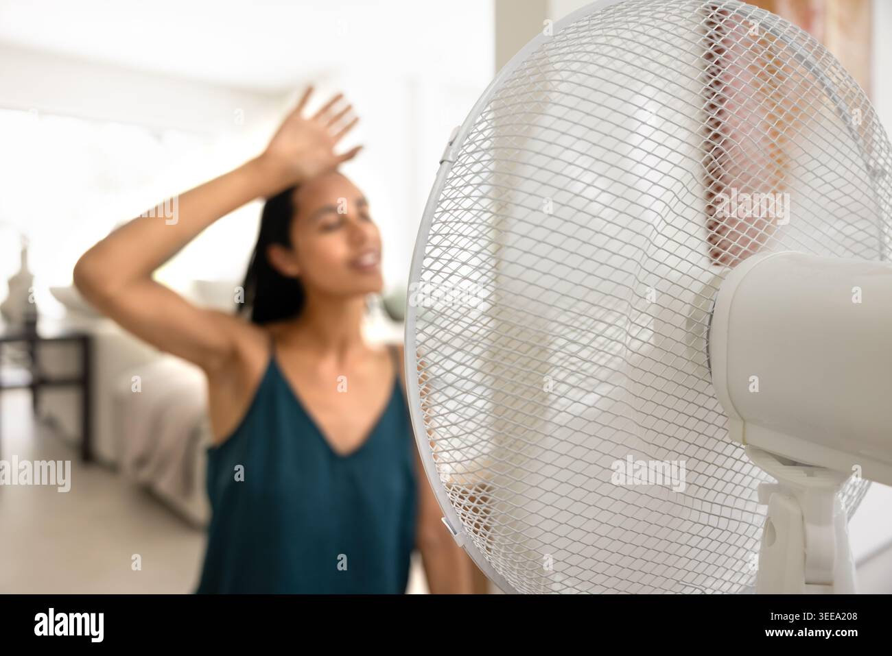 Woman feeling hot and cooling down with fan Stock Photo
