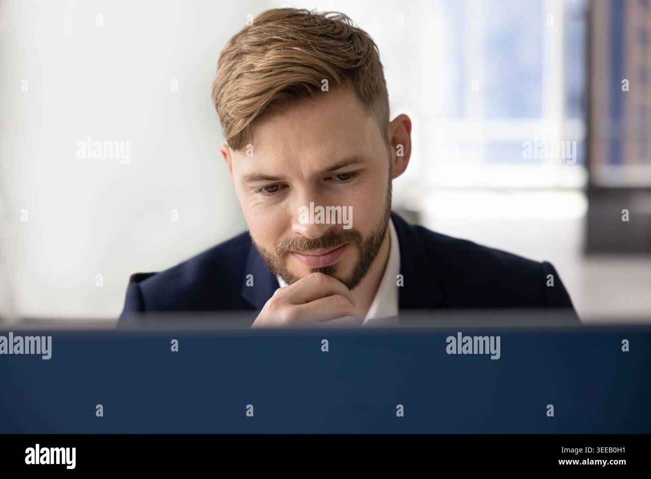 Man looking at computer screen with thoughtful expression Stock Photo