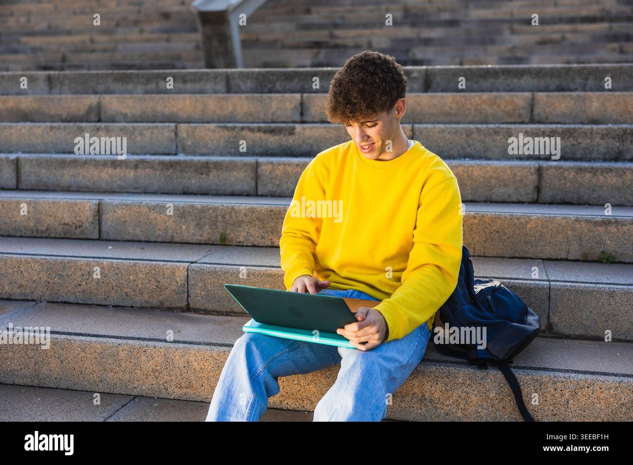 College student studying on laptop outdoors on steps Stock Photo