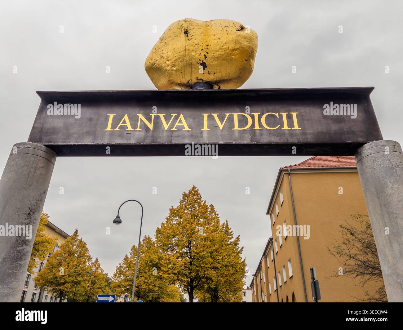 The Gate with the Golden Stone is a work of art by Heinrich Brummack. A golden stone balances menacingly on a steel girder above the exit of the Akazienweg underground station. The Latin inscription ‘Ianva Ivdicii’ translates as ‘The Gate of Judgement’. In Cologne vernacular, the artwork is known as the ‘Monument to the Fare-Dodger’. Cologne, North Rhine-Westphalia, Germany Stock Photo