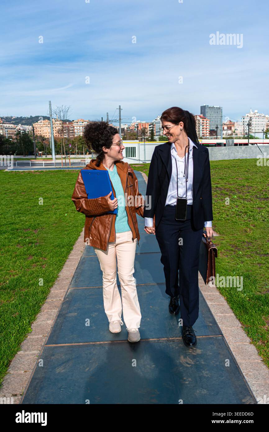 Diverse businesswomen walking and discussing in urban park Stock Photo