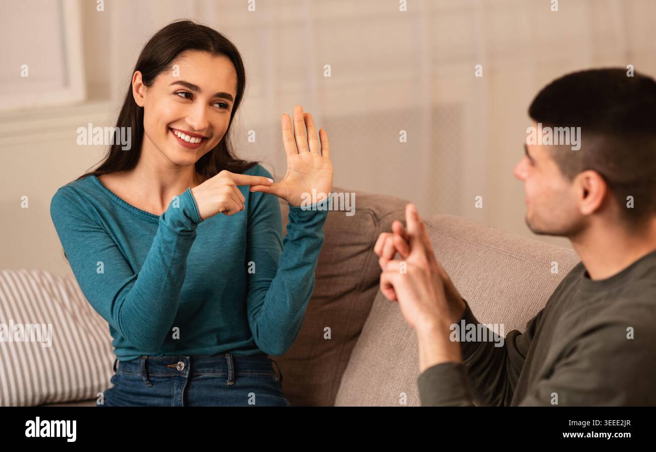 Couple Sitting On Sofa Communicating With Sign Language Stock Photo