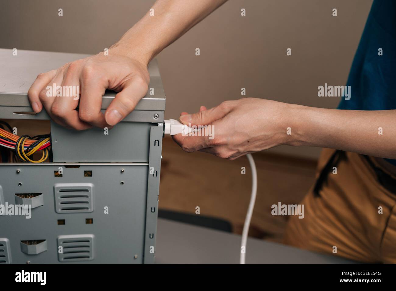 Person connecting power cable to computer desktop system unit, installing power supply for technology hardware and electronic device setup, preparing Stock Photo