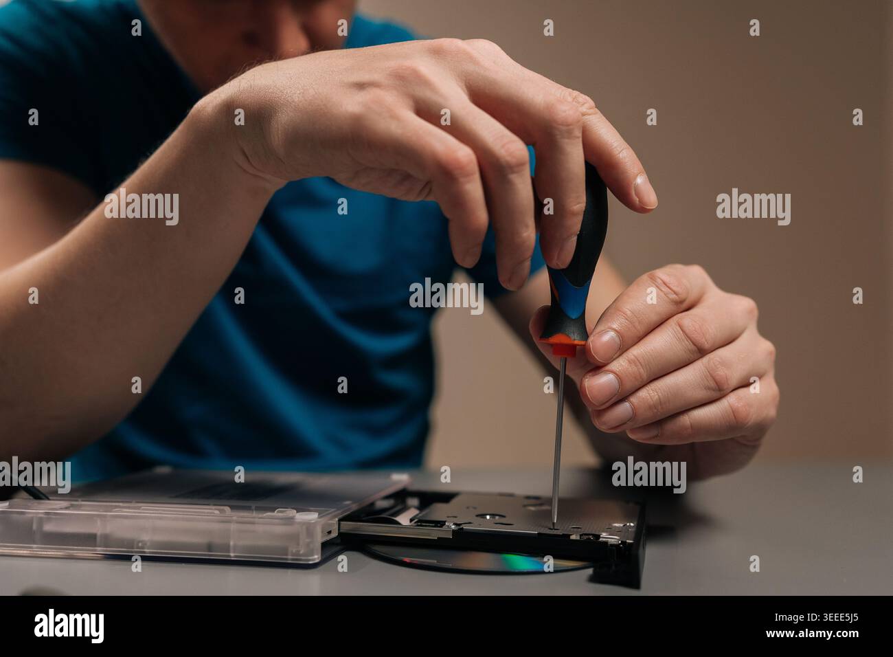 Technician repairing external optical disc drive, performing maintenance on the hardware, disassembling the casing of the cd dvd reader writer on a ta Stock Photo
